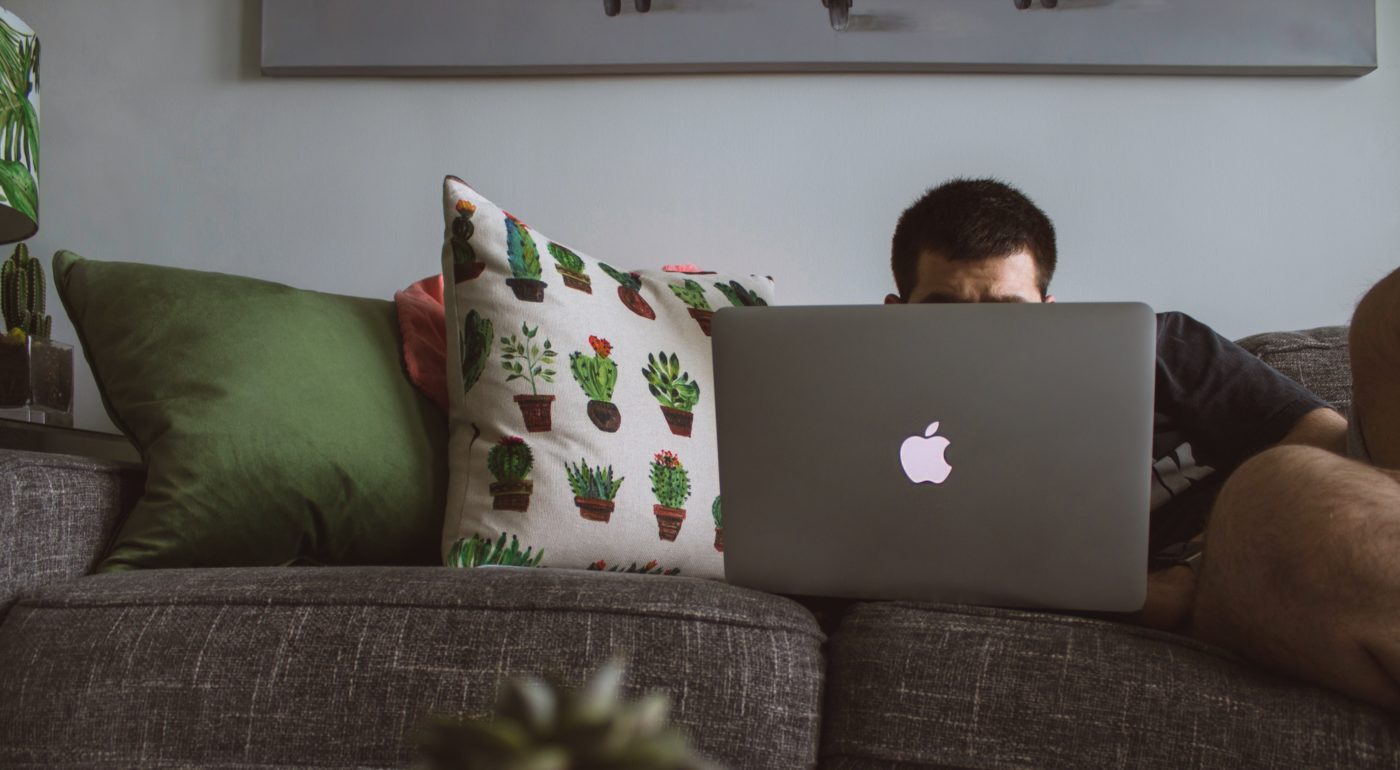 Man on laptop while lying on couch