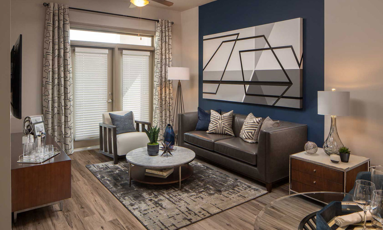 Living area with accent wall, wood like floors, double doors to patio, and typical furniture