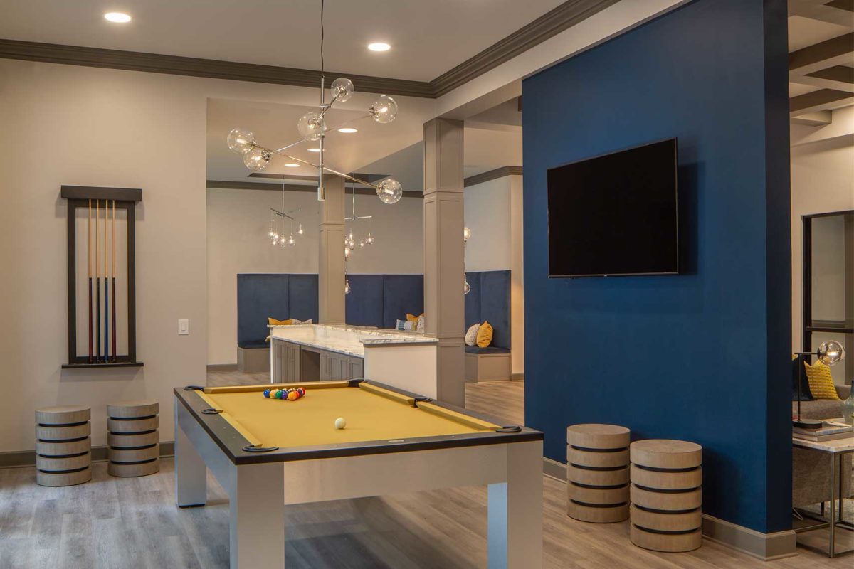 Clubhouse room with wall mounted TV, pool table, designer seating and pendant lighting