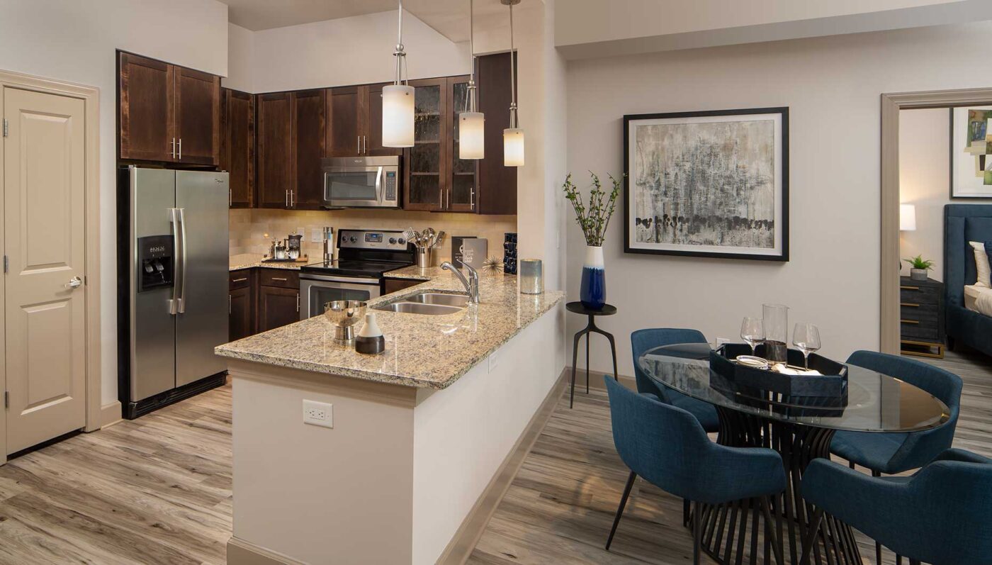 Kitchen with stainless steel appliances, dining area with table, granite counters and double basin sink